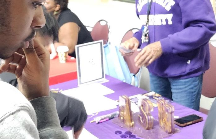  student standing a table for ASU during a college fair